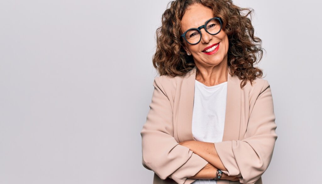 Middle age beautiful businesswoman wearing glasses standing over isolated white background happy face smiling with crossed arms looking at the camera. Positive person.