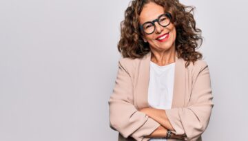 Middle age beautiful businesswoman wearing glasses standing over isolated white background happy face smiling with crossed arms looking at the camera. Positive person.