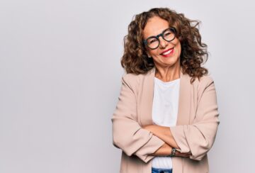 Middle age beautiful businesswoman wearing glasses standing over isolated white background happy face smiling with crossed arms looking at the camera. Positive person.