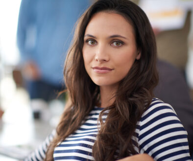 Her work stands out from the crowd. Portrait of an attractive young woman sitting in an office with colleagues in the background.