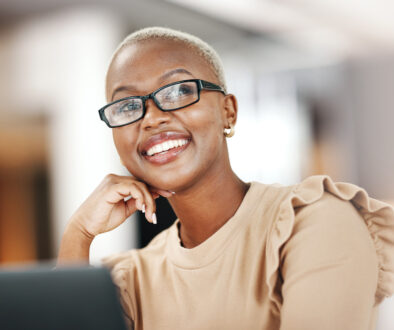 Black woman, thinking and smile, relax at desk with laptop for content creation ideas at digital marketing startup. Copywriter, happy female and contemplating with inspiration for copywriting job