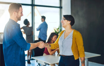 Handshake, woman and man in creative meeting with smile, introduction and collaboration in office together. Workshop, agreement and business people shaking hands at design agency for happy welcome.
