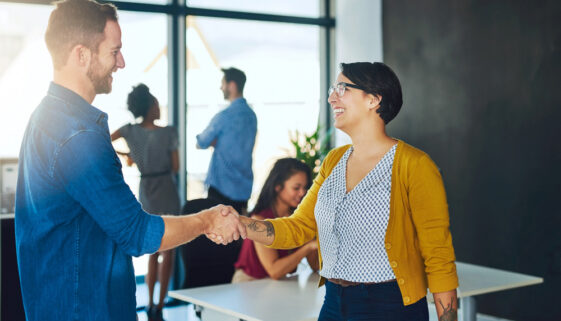 Handshake, woman and man in creative meeting with smile, introduction and collaboration in office together. Workshop, agreement and business people shaking hands at design agency for happy welcome.