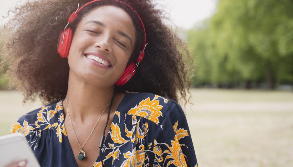 enthusiastic-woman-listening-to-music-with-headphones-and-mp3-player-in-park-595347193-59d51128396e5a0011e8cd06