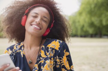 enthusiastic-woman-listening-to-music-with-headphones-and-mp3-player-in-park-595347193-59d51128396e5a0011e8cd06