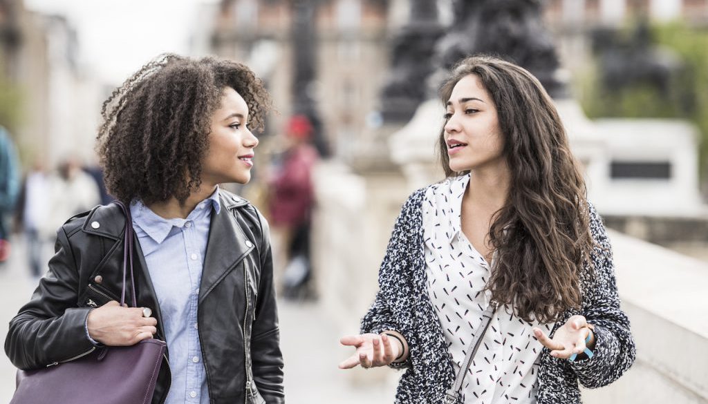 Two female friends talking outdoors in Paris, France