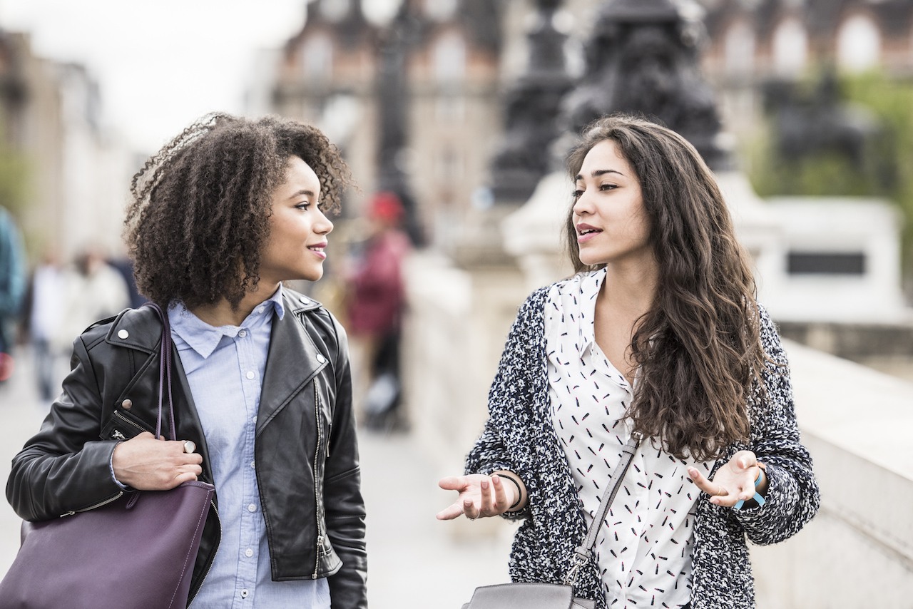 Two female friends talking outdoors in Paris, France