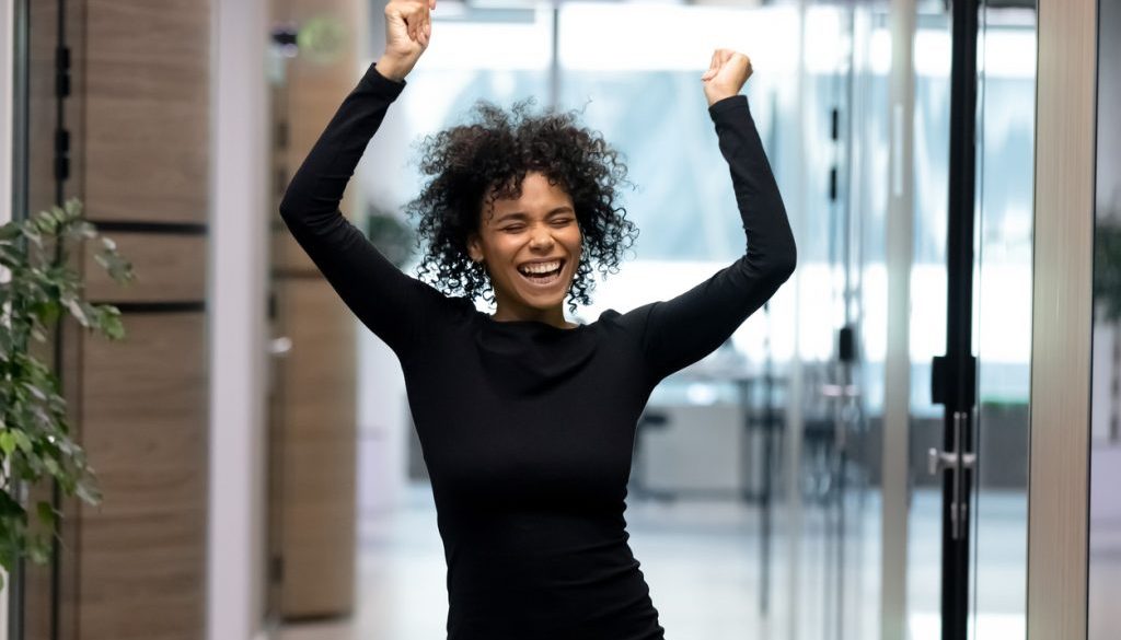 Overjoyed African American female employee dance celebrating success