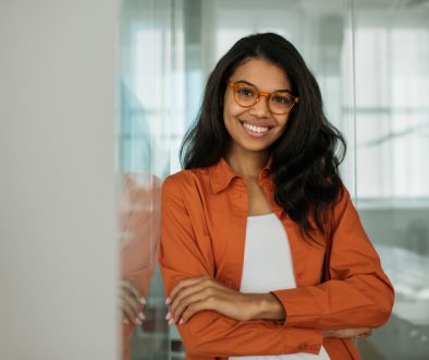 Smiling African American business woman wearing stylish eyeglasses looking at camera standing in modern office. Successful business and career concept