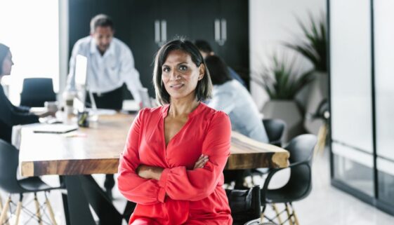 Portrait of hispanic transgender woman sitting on wheelchair with arms crossed in the office in Latin America