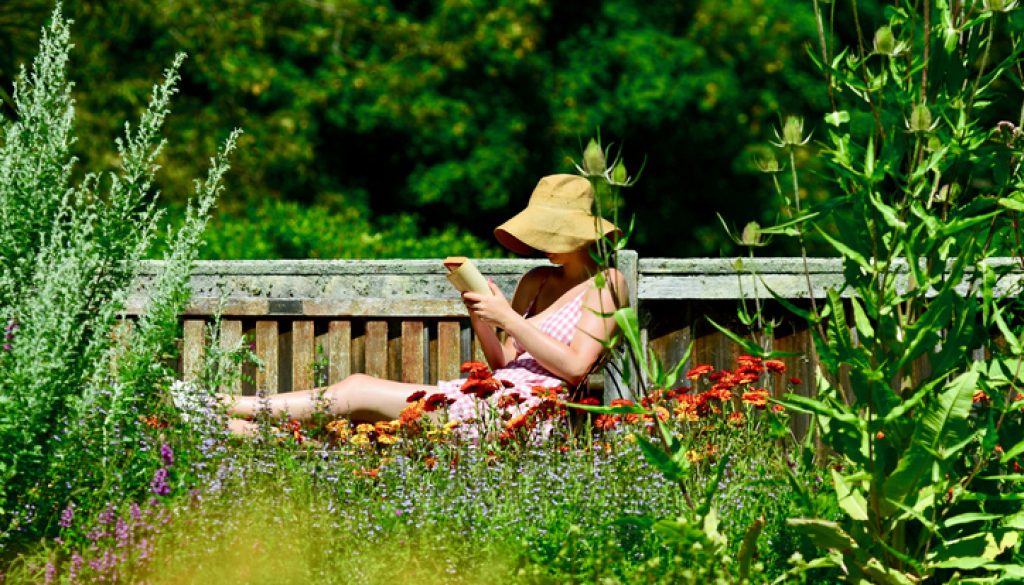 A young lady reading in a botanical garden.