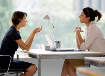 two woman at work across desk profiles