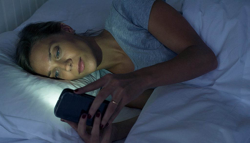 Woman lying in bed using smartphone