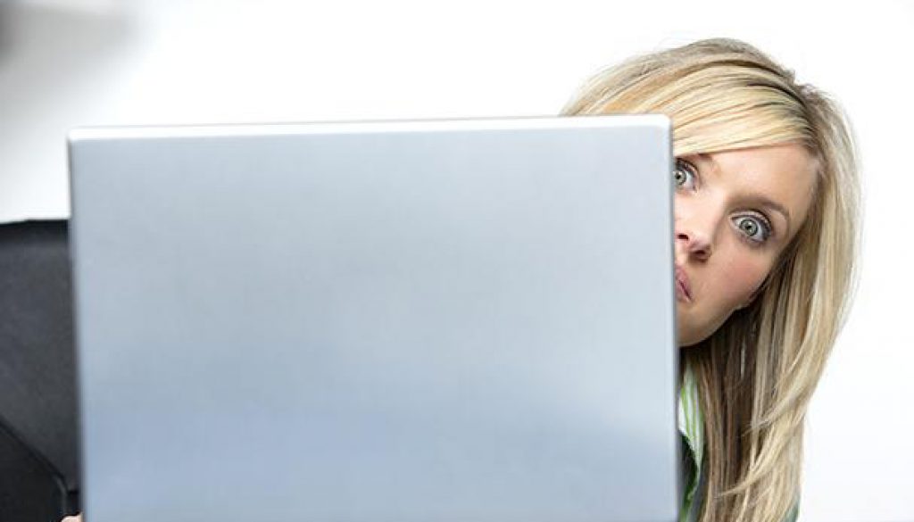 woman peeking behind computer