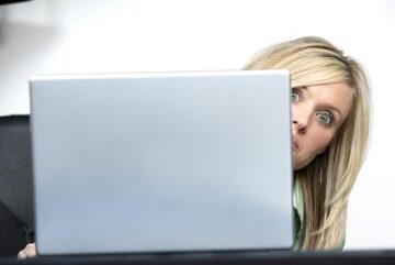 woman peeking behind computer